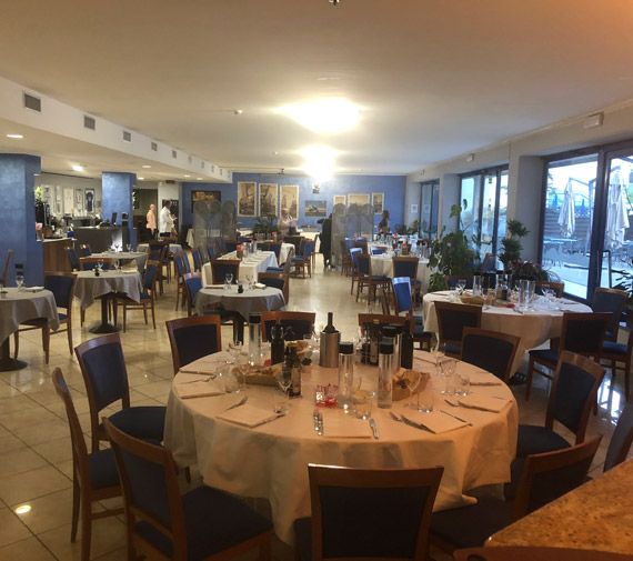 Dining room of the Rosa Blu Restaurant with laid round tables
